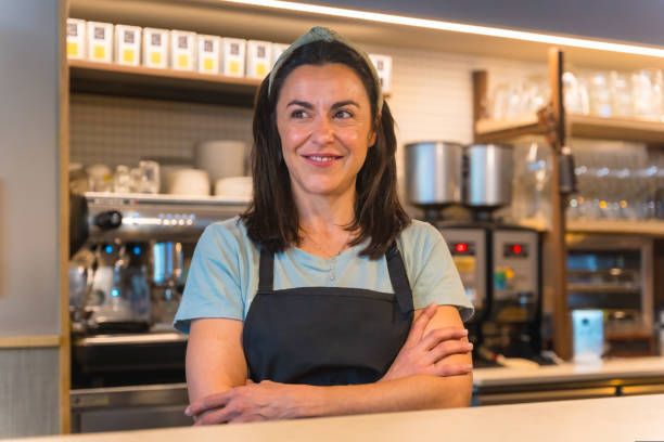 istock Smiling waitress with a coffee machine in the background 1454969047