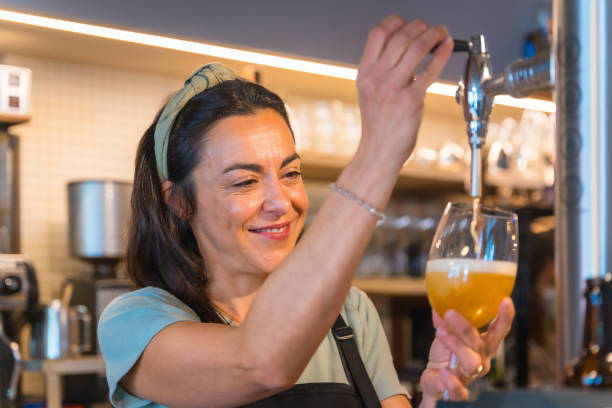 istock Smiling waitress brewing a blonde beer on the tap 1454969051