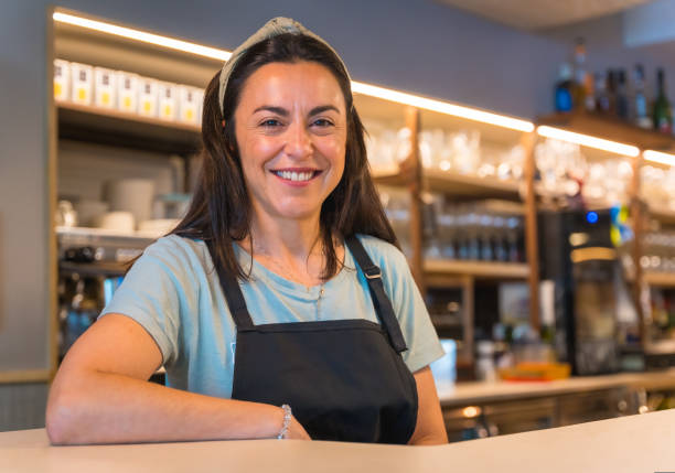 istock Smiling waitress with a coffee machine in the background 1454969056