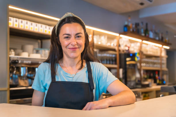istock Smiling waitress with a coffee machine in the background 1454969064