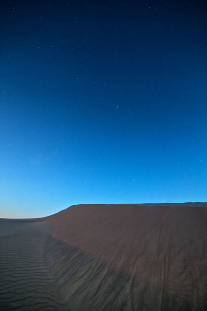 istock Vertical shot of dune with beautiful starry sky above it 1454971739