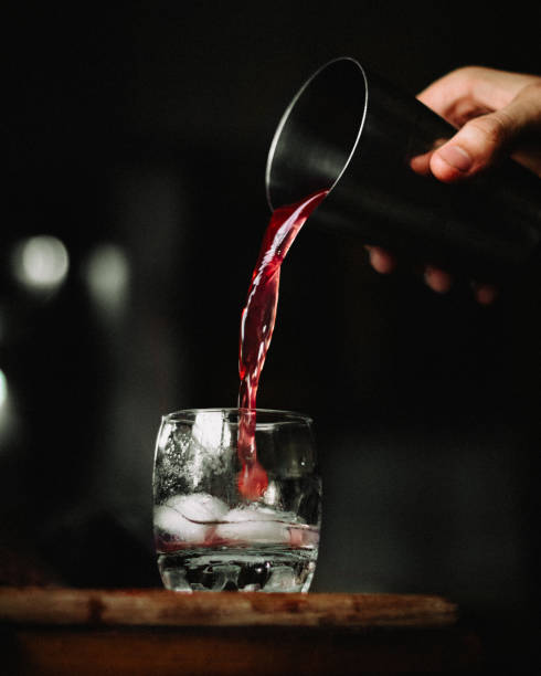 istock Vertical shot of red, cherry, alcoholic drink with ice under lighting on a black background 1454972571