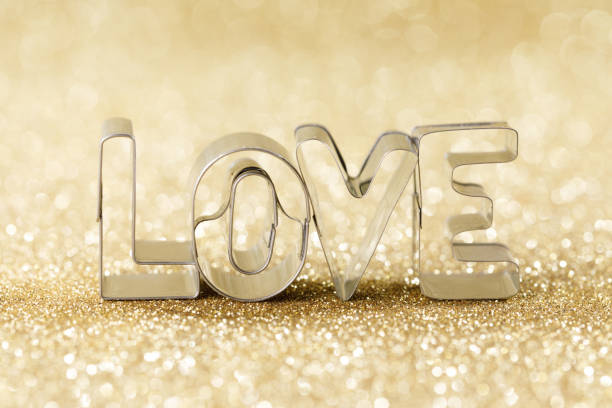 Word LOVE on golden bright glitter lights bokeh background