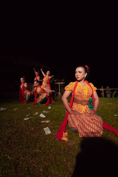 un groupe de danseurs indonésiens se produisant sur scène avec un foulard rouge et une robe orange traditionnelle à l’intérieur du festival - religion spirituality serene people tranquil scene photos et images de collection