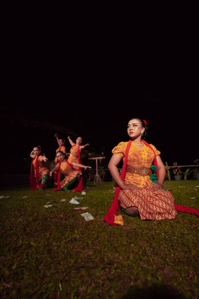 un groupe de danseurs indonésiens se produisant sur scène avec un foulard rouge et une robe orange traditionnelle à l’intérieur du festival - religion spirituality serene people tranquil scene photos et images de collection