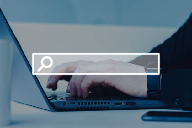 istock Male hand typing on a laptop in the office with a visual  screen search button 1454977824
