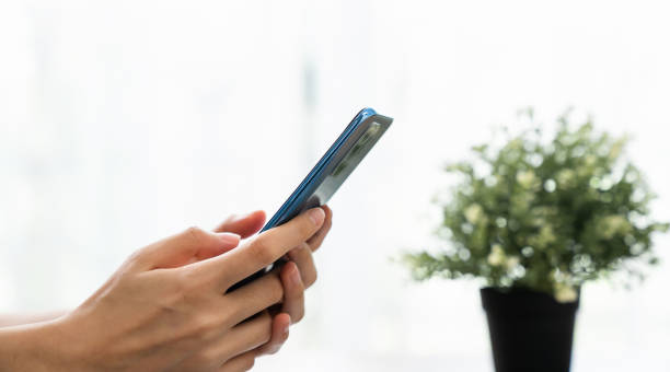 istock Hand holding smartphone with using social media on internet on sofa in living room. 1454977939