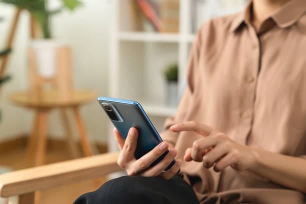 istock Hand holding smartphone with using social media on internet on sofa in living room. 1454977946
