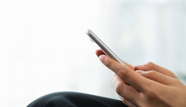 istock Hand holding smartphone with using social media on internet on sofa in living room. 1454977948