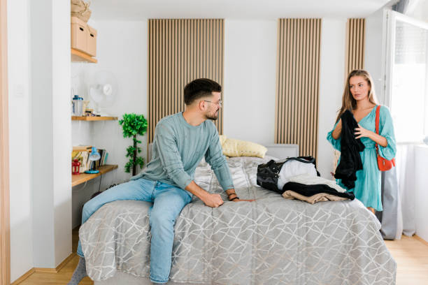 istock Young Couple Having Relationship Difficulties, Woman packing and leaving after fight 1454977961