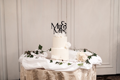 A beautiful two-tier wedding cake with Mr & Mrs topper decorated with flowers