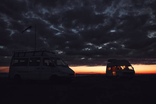 istock Camper van silhouette in nature near lake during sunset. 1454983052