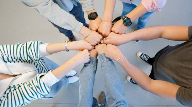 Coworkers joining hands in the office