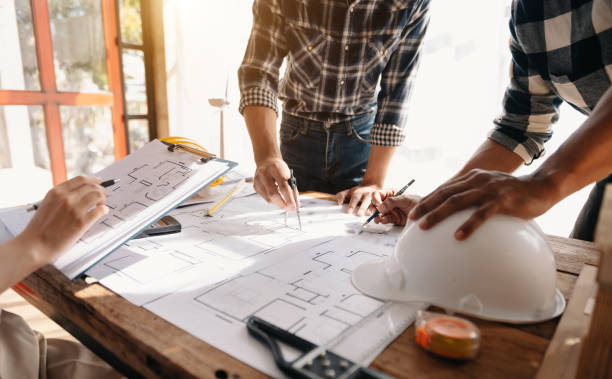 istock wo colleagues discussing data working and tablet, laptop with on on architectural project at construction site at desk 1454984734