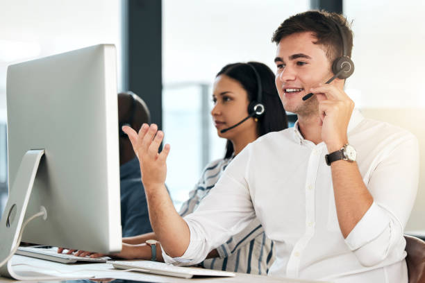 istock Computer customer support and crm man employee on an office phone consultation. Speaking internet and web call center employee consultant with headset working on tech consulting and telemarketing 1454986768
