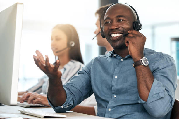 istock Call center, black man and talking for customer service, smile and headset in office. Telemarketing, happy male consultant or client support for sales growth, consulting and conversation for business 1454986819