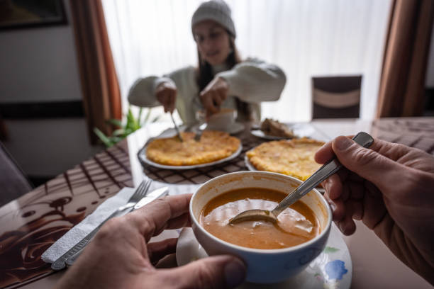 Close up on human hand holding a spoon and picking chinese dumplings from bowl.