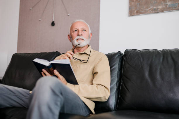 istock Senior Man reading book at home 1454993342