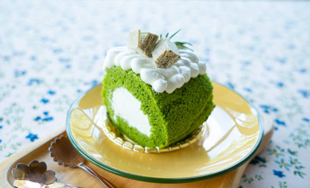 istock Matcha roll cake decorated with whipped cream on top. Wan in a light brown dish 1454993538