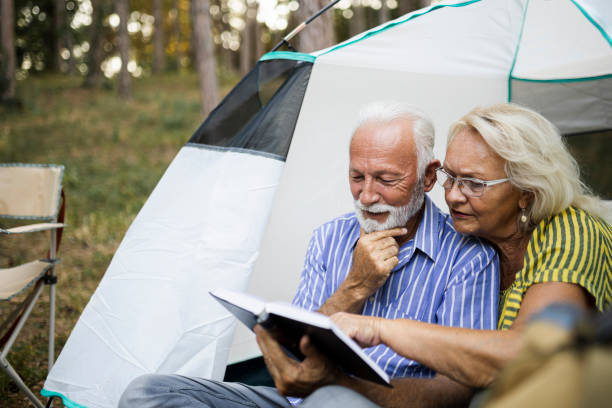 istock Senior couple enjoying a book on the camping 1454993739