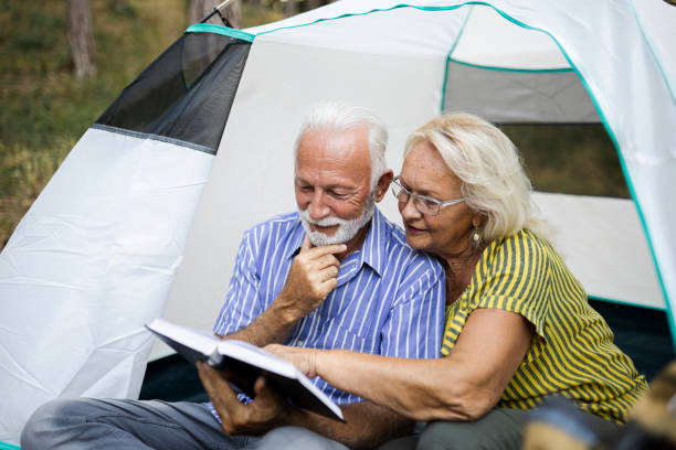 istock Senior couple enjoying a book on the camping 1454993759