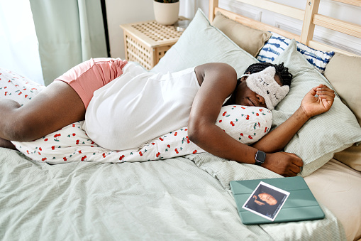 Pregnant woman relaxing during the day, sleeping with face mask on