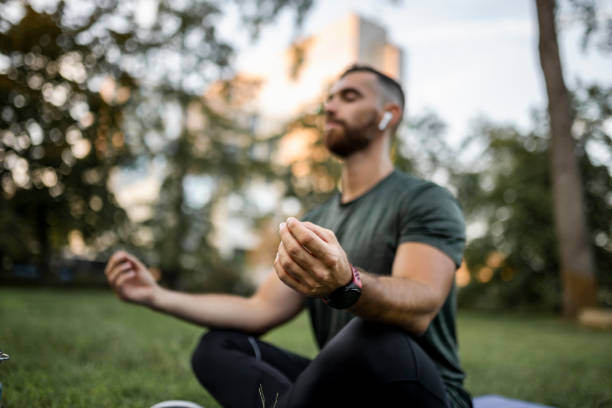 istock Young man meditating outdoors at park 1454998722