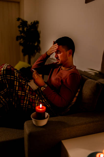 istock During an electricity crisis, a young man with flu is checking his temperature. 1454999589