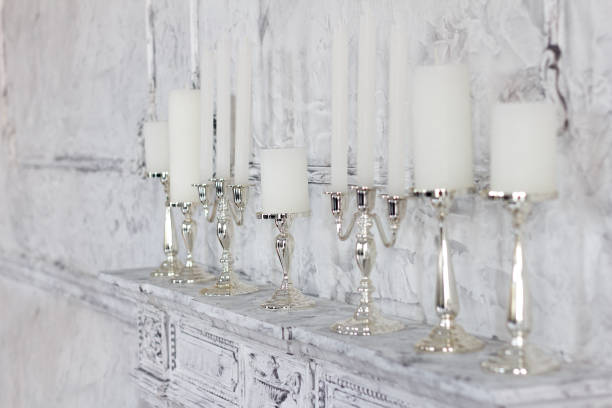 Elegant interior, white candles in elegant candlesticks stand on a fireplace in the room stock photo
