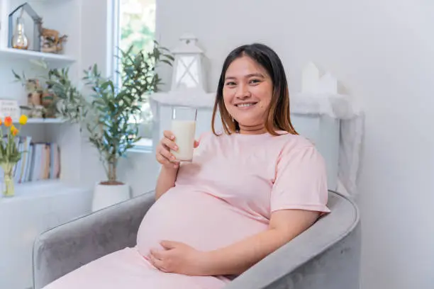 Asian pregnant woman drinking milk and stay at home alone. family lifestyle.