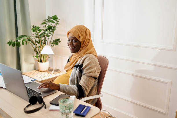 Pregnant  black muslim woman working from office