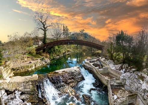 A scenic view of a bridge in the woods at sunset in Puente Viesgo, Spain