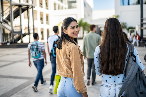 Portrait of a young woman walking with her friend at university