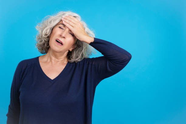 istock Mature woman with hand on forehead expressing headache 1455012700