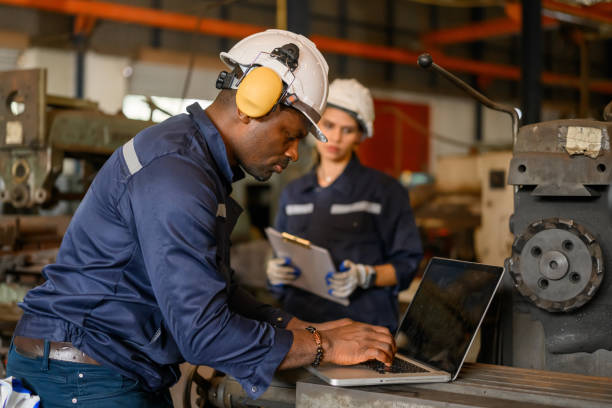 istock Male technician specialist with safety uniform using laptop checking and controlling machinery at manufacturing plant 1455013585