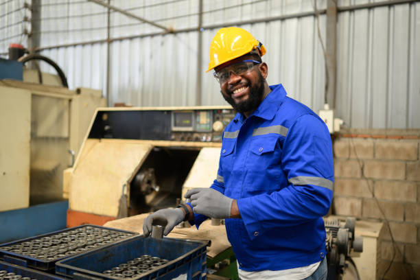 retrato de un ingeniero trabajador seguro de sí mismo sonriendo y trabajando en la fábrica - african descent factory accuracy analyzing fotografías e imágenes de stock