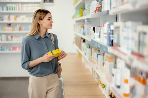 Young Female Purchaser Choosing Product at Pharmacy