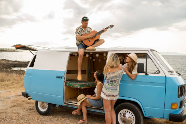 istock Man playing the guitar on a van with a group of friends 1455018126