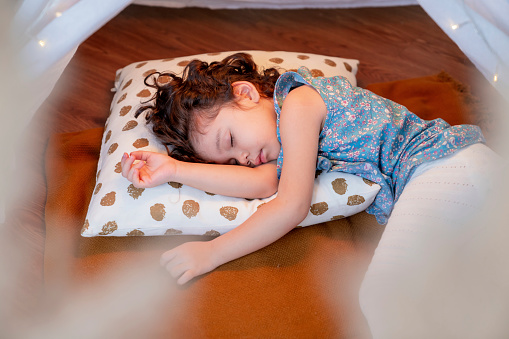 adorable white caucasian girl child fall in sleep on the floor after all day playing with her family,girl in a blue casual cloth, lying on the floor in living room at home