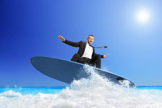 Businessman riding a surfboard on a sea wave stock photo