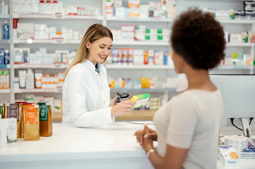 Pharmacy Drugstore: Beautiful Female Pharmacist Scanning Medicine's Barcode in a Pharmacy