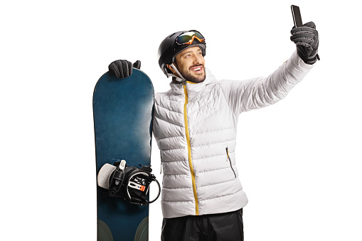 Man with a snowboard taking a selfie with a smartphone isolated on white background