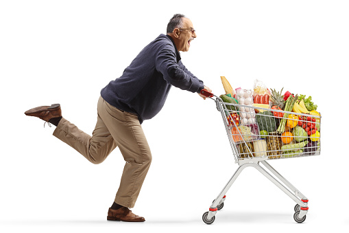 Excited mature man running with a shopping cart isolated on white background