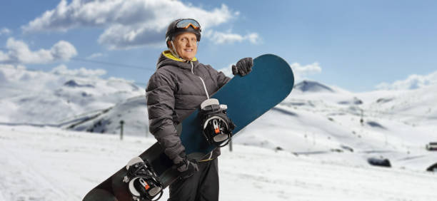 istock Mature man with a snowboard standing on a mountain 1455018769