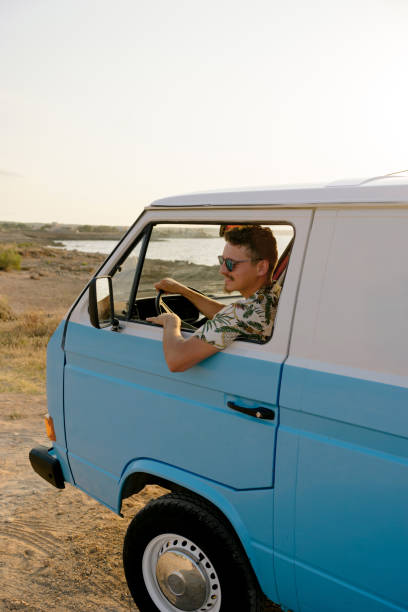 istock Vertical photo of a man driving a retro camper van 1455019353