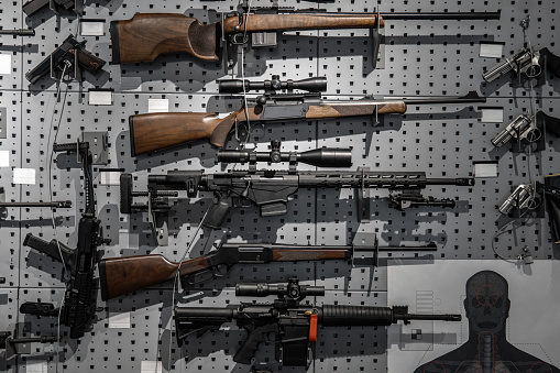 Collection of rifles and carbines. Various firearms hang on special mounts on the wall. Weapon background.