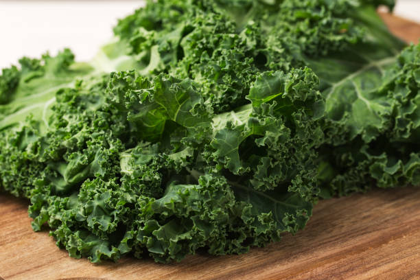 Curly Kale on a wooden cutting board. Healthy eating concept. Superfoods. Organic food. Curly Kale on a wooden cutting board. Healthy eating concept. Superfoods. Organic food. kale stock pictures, royalty-free photos & images