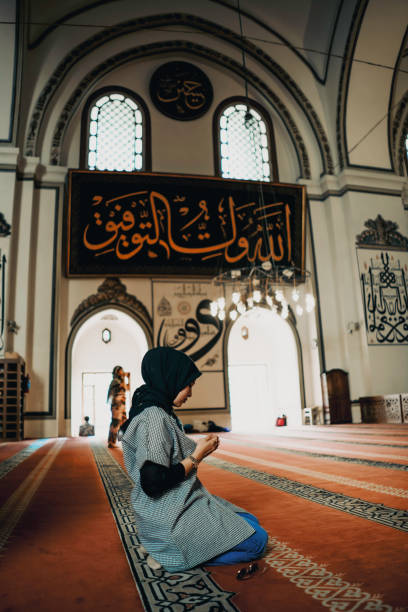 istock Side View Of woman Praying While Kneeling At Mosque 1455022698