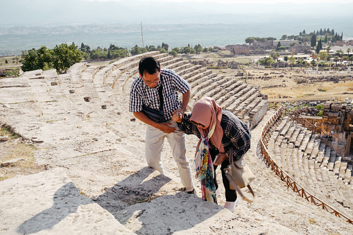 senior couple Tourist in the Ancient Roman Amphitheater Ruin the The Holy City of Hierapolis next to the Pamukkale hot springs in Western Turkey built in the 2nd Century and is now a UNESCO World Heritage Stie