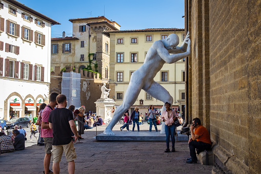 Florence, Italy - October 18, 2022: the monumental sculpture Mr. Arbitrium, by Emanuele Giannelli. A colossus of almost six meters seems to support the Basilica of San Lorenzo. The temporary sculpture, was located in Piazza San Lorenzo from September 2 to October 31, 2022.